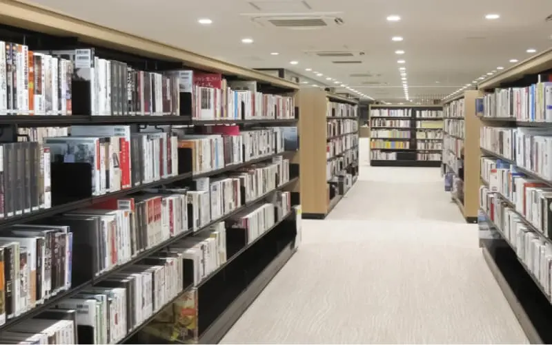 通路の両側に書棚が並ぶ図書館の室内