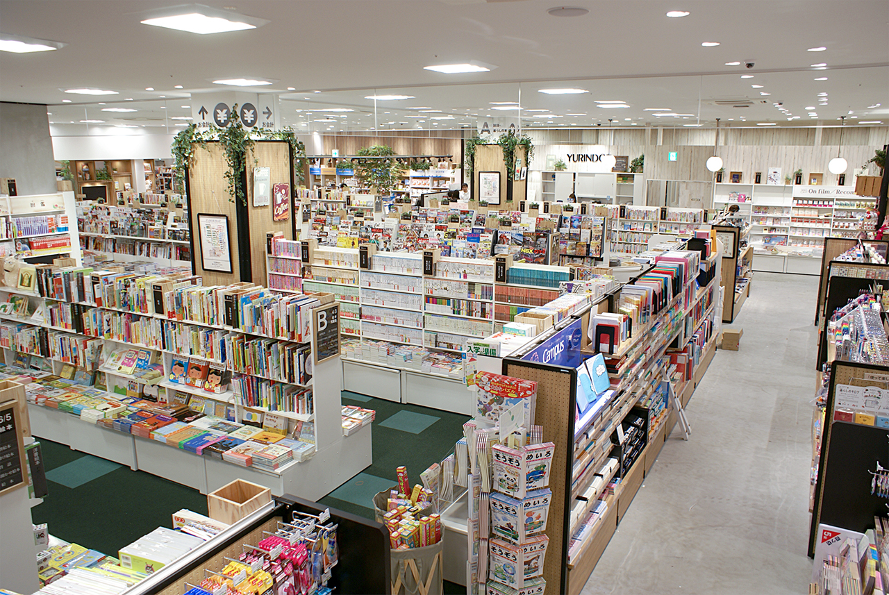 書籍売場の俯瞰。ナチュラルな色の店内、フロア中央は背の低い書棚が並ぶ